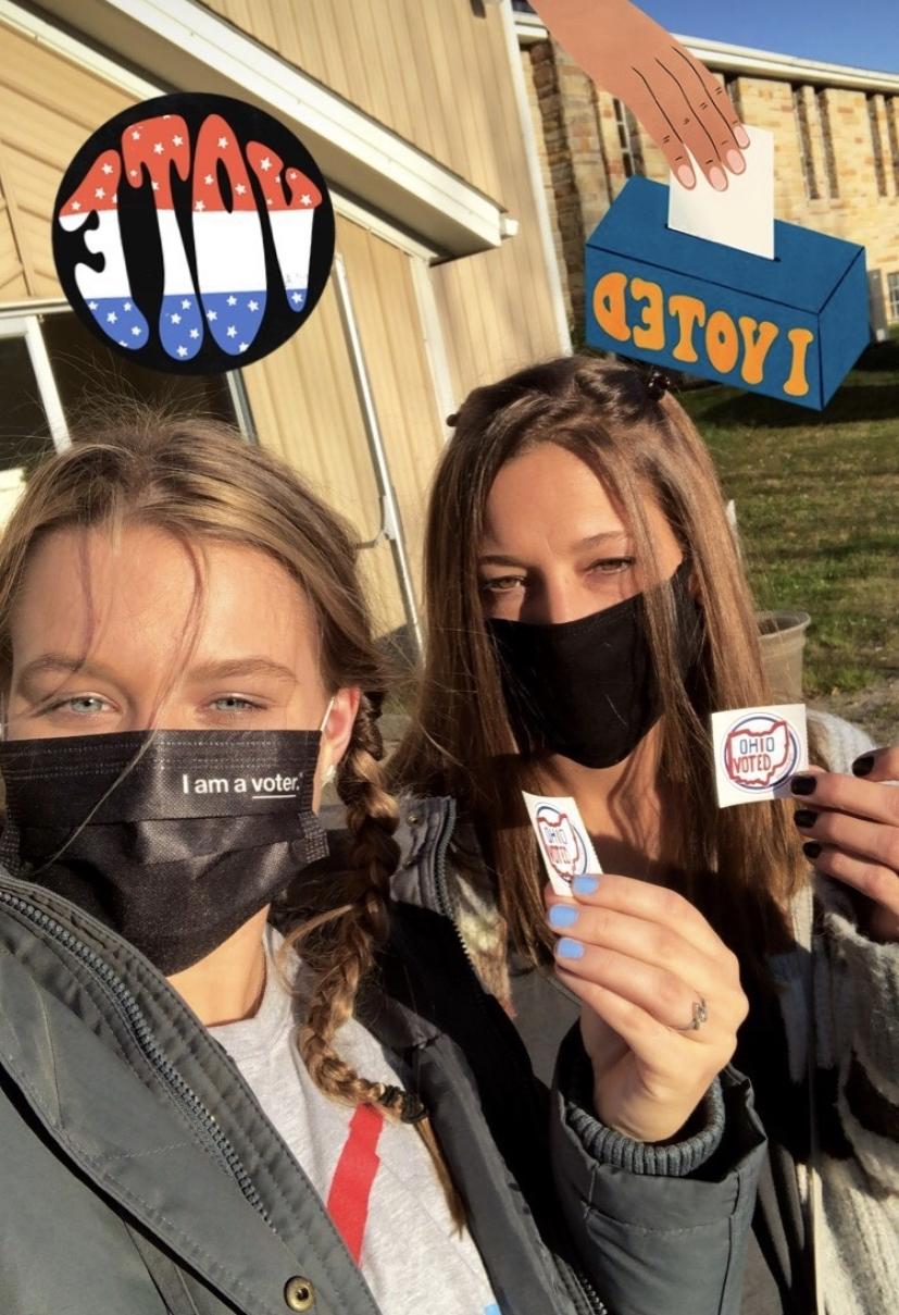 two students holding up voting stickers